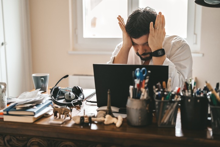 Tired frustrated exhausted businessman working from home online sitting at home office with laptop during quarantine and self isolation period at pandemic. Crisis management. Despair of market falling down.