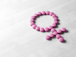 Medicine for woman. Menopause, pms, menstruation or estrogen concept. Female health. Gender symbol made from pink red pills or tablets on wooden table.