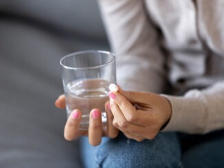 Close up sick woman holding glass with water and pill in hands
