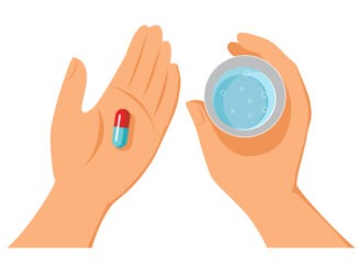 Hands holding pills and glass of water in hands.