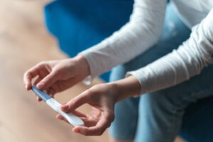 Woman hands holding pregnancy test when sitting on sofa