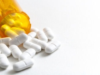 Hydrocodone capsules spilling out of a prescription bottle with copyspace