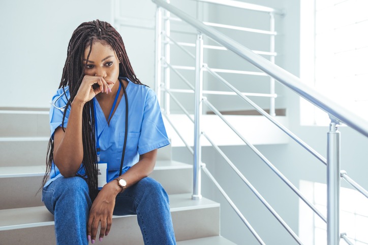 Shot of a young nurse looking stressed out while sitting at a window in a GP surgery.