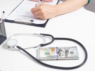 A stethoscope and money lie on a white medical table at the doctor's
