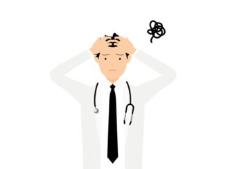 Male doctor in white coat holding head feeling burntout
