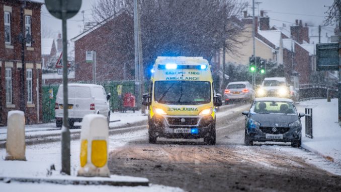 NHS EMAS Ambulance Service on 999 emergency response with snow on road blue lights during snowfall