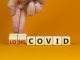 Long covid symbol. Doctor turnes wooden cubes and changes words 'covid' to 'long covid'. Beautiful orange background, copy space. Medical, covid-19 pandemic long covid concept.
