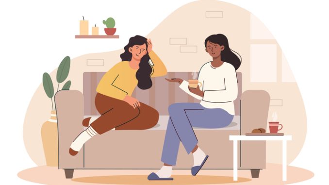 Women drinking coffee sit on couch spending time together and chatting