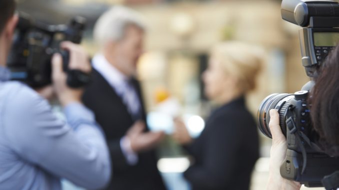 Photographer Taking Pictures Of Female Journalist Interviewing Businessman