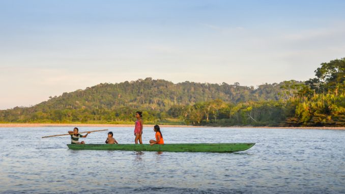Local Quechua tribe teenagers in the Ecuadorian Amazon on a canoe on the river Napo
