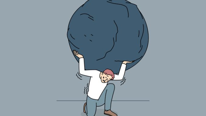 Stressed man carrying heavy stone on shoulders