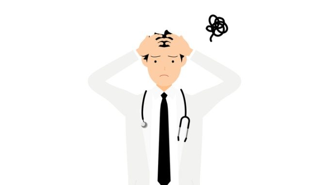 Pose of male doctor in white coat holding head and puzzling