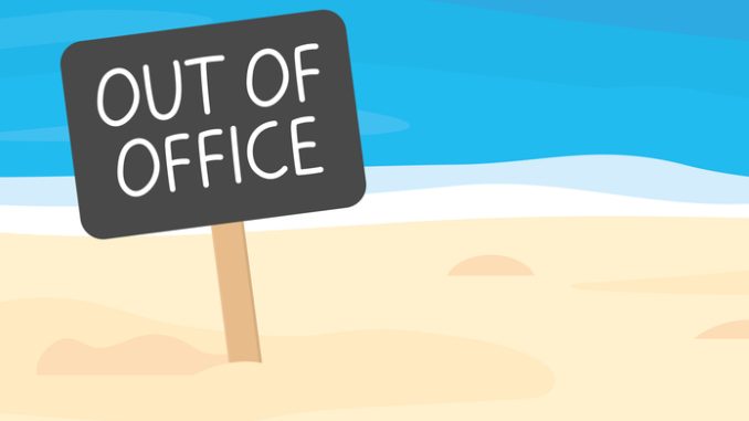 out of office written on sign board on sandy beach