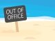 out of office written on sign board on sandy beach