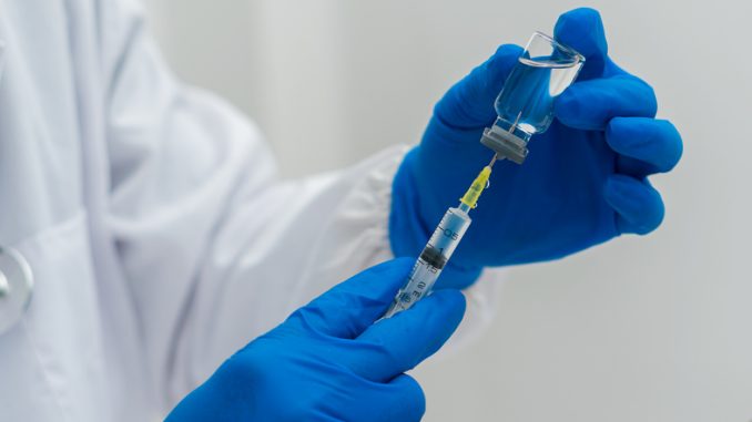 Doctor hand holding a syringe and drawing vaccine from a vial