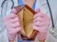 A doctor in medical gloves shows an empty wallet.