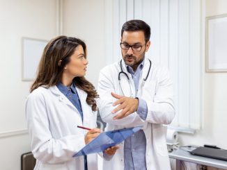 Doctors discussing over a medical report in hospital.