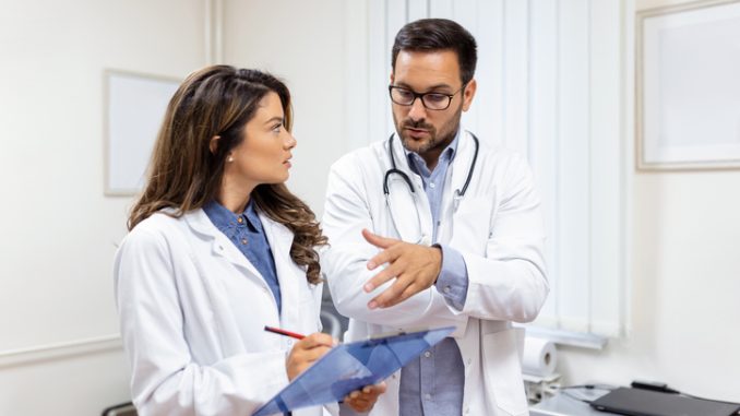 Doctors discussing over a medical report in hospital. 