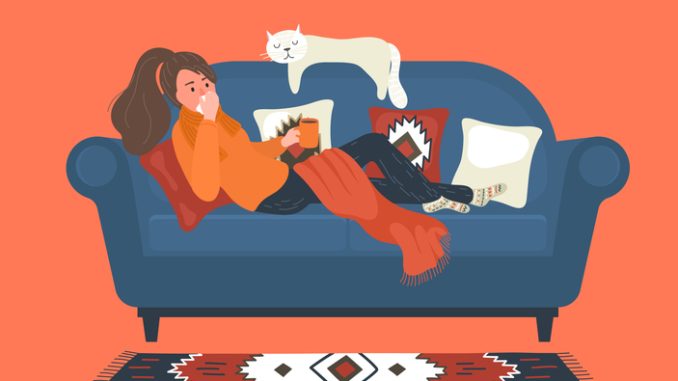 Flu. Ill woman lays on sofa at home and blowing her nose.
