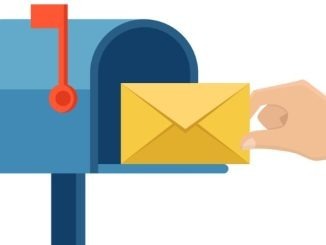 Hand holds letter and inserts it into mailbox