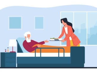 Female caregiver gives food to elderly man in bed,