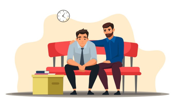 Depressed man sits at sofa, colleague support, belongings in box. 