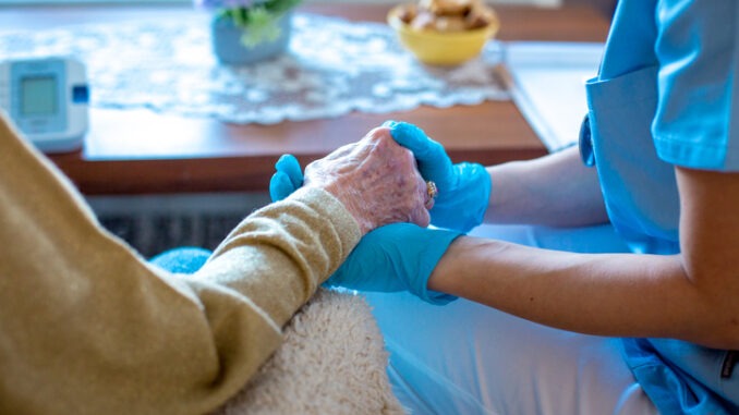 Young female doctor is holding her patient's hand, comforting her. Old lady is worried and doctor is there to take care of her every need. Old lady is in trusting hands.