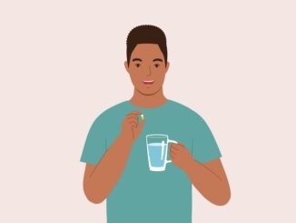 One Smiling Man Taking Pill With A Glass Of Water.