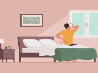 Man waking up and suffering from back pain, he is sitting on the bed and touching his neck and lower back