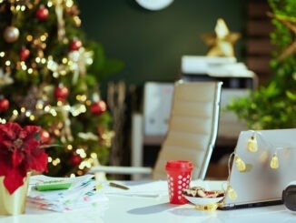 modern Christmas decorated green office with laptop, poinsettia, Christmas beverage and cookies.