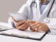 Consultation Online. Unrecognizable male doctor using smartphone at workplace, messaging with his patient, prescribing treatment