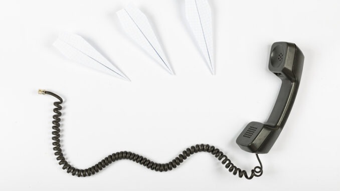Call center concept, public relations, gossip, rumors. Telephone receiver with wire on a white background and paper airplanes.