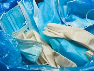 Medical trash. Coronavirus protection equipment in medical waste bin. Used face masks and sterile gloves. Doctor uniform for patient treatment in hospital. Prevention the spread of COVID-19.