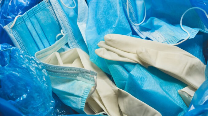 Medical trash. Coronavirus protection equipment in medical waste bin. Used face masks and sterile gloves. Doctor uniform for patient treatment in hospital. Prevention the spread of COVID-19.