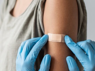 Doctor putting plaster at female hand after injection of a corona virus vaccine. Corona virus protection, self care, healthy lifestyle, vaccination concept.