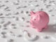 Pink piggy bank standing among white question marks on white background. Illustration of the concept of investment strategies and economic forecast