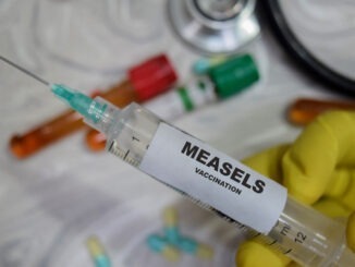 Measels vaccination drug syringe in yellow gloved hands. Medical concept