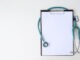 Blank medical clipboard with stethoscope on white background. Copy space.