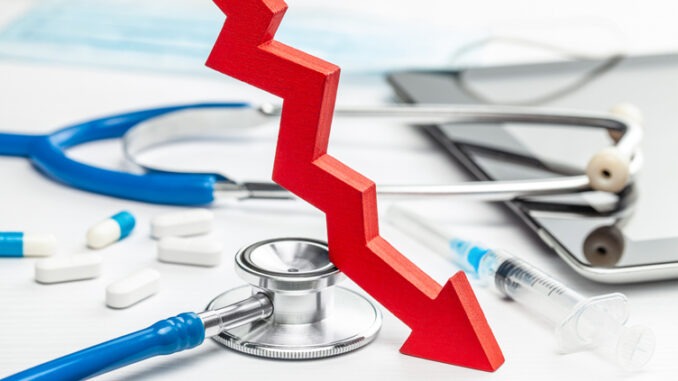 Red down arrow and medical devices. White background with stethoscope, syringe and pills.