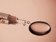 Injection syringe with a drop of drug on a stainless steel background. High quality photo. Color of the Year 2025 Mocha Mousse.