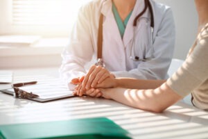 Doctor and patient are discussing something in clinic, just hands at the desk. Medicine and best service concept.