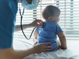 Asian female Pediatrician doctor examining her little baby patient with stethoscope in medical room at hospital.