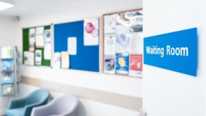 Shallow focus of a typical NHS hospital waiting room sign seen in a British hospital. Seating and information material can be seen in the room.