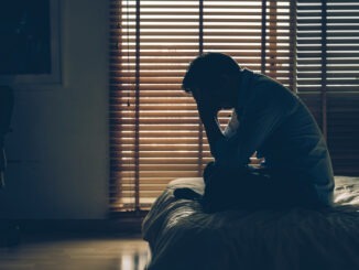 Sad businessman sitting head in hands on the bed in the dark bedroom with low light environment, dramatic concept, vintage tone color