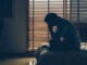 Sad businessman sitting head in hands on the bed in the dark bedroom with low light environment, dramatic concept, vintage tone color
