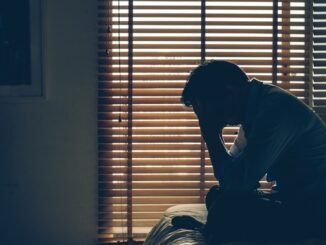 Sad businessman sitting head in hands on the bed in the dark bedroom with low light environment, dramatic concept, vintage tone color