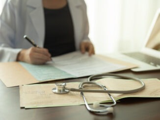 stethoscope and electrocardiogram on medicine report with doctor woman notes information patient medical history at the hospital.
