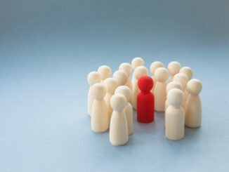 A socially diverse person being surrounded and protected by a crowd of people for being different. Alternatively a Manager or boss at a pep rally being surrounded by workers and team mates