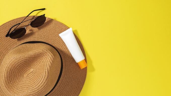 Things for beach sunscreens, hat and sunglasses. Safe exposure to sun. Skin Cancer Awareness Month Concept. Top view. Copy space