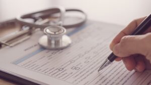 closeup pen in hand's doctor notes data on medical document.